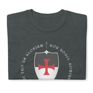 May include: A dark heather grey t-shirt with a white circle design featuring a red cross on a shield and the text "Non Nobis, Domine, Non Nobis, Sed Nomini Tuo Da Gloriam".
