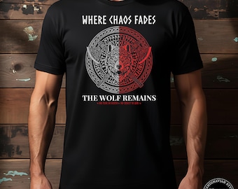以下が含まれることがあります： 「WHERE CHAOS FADES」と「THE WOLF REMAINS」の文字とオオカミのデザインが施された黒いTシャツ。デザインにはオオカミの頭、斧、赤とグレーの円形模様が含まれています。Tシャツはクルーネックです。