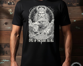 May include: Black t-shirt featuring a detailed black and white illustration of a Viking figure and a raven. The text "EYES OF THE GODS SEE ALL" is printed below the illustration. The shirt is from "Hygge & Hype, Voices of the North."