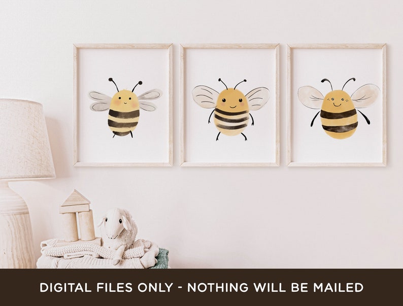 May include: Three printable art prints featuring watercolor illustrations of cute cartoon bees with yellow and black stripes. The bees have smiling faces and are set against a white background.