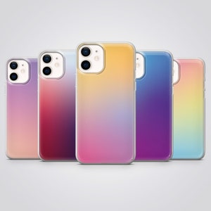 Puede incluir: Cinco fundas de teléfono diferentes con diseños de colores degradados. Las fundas son todas transparentes y muestran las lentes de la cámara del teléfono. Los colores son rosa, morado, azul, amarillo y rojo.