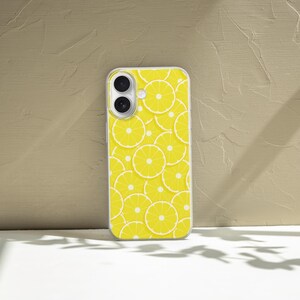 May include: A clear phone case with a yellow lemon slice pattern. The case has a cutout for the camera lens.