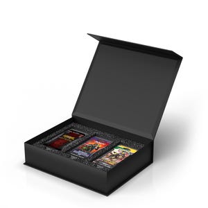 May include: A black rectangular presentation box with a hinged lid, containing three trading card booster packs nestled in black foam inserts. The packs feature colorful graphic illustrations and branding, including text such as Modern Horizons II.