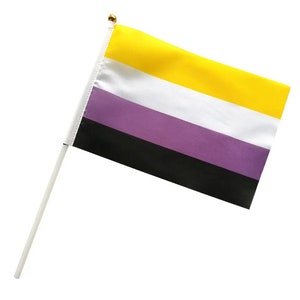 Könnte beinhalten: Eine kleine Handflagge mit einem Muster aus horizontalen gelben, weißen, violetten und schwarzen Streifen. Die Flagge ist an einem weißen Stock befestigt.