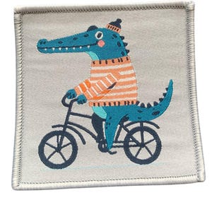 May include: A blue alligator wearing a striped orange and white sweater rides a bicycle with black wheels. The alligator has a red nose and a black hat.