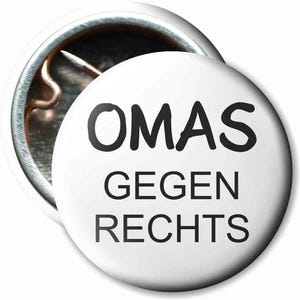 May include: White button with black text that reads "OMAS GEGEN RECHTS".