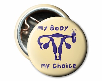 May include: A yellow button with a purple uterus and a hand with a middle finger raised. The text on the button reads "My Body My Choice".