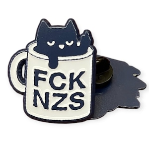 Könnte beinhalten: Ein dunkelblauer Emaille-Pin mit einer schwarzen Katze in einer weißen Tasse. Auf der Tasse steht in schwarzen Buchstaben "FCK NZS". Die Katze zeigt den Mittelfinger. Der Pin hat einen schwarzen Pin-Rücken.