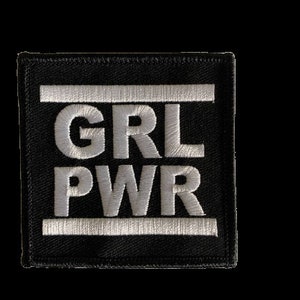 Könnte beinhalten: Schwarzer gestickter Aufnäher mit weißem Text, der "GRL PWR" lautet