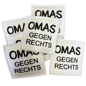 Könnte beinhalten: Eine Ansammlung quadratischer, weißer Stoffaufnäher mit schwarzem, gesticktem Text, der OMAS GEGEN RECHTS lautet. Jeder Aufnäher hat einen sauberen weißen Rand und eine kräftige, serifenlose Schrift, die in drei Zeilen angeordnet ist.