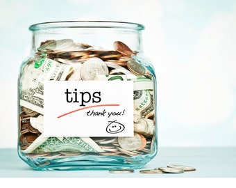 Könnte beinhalten: Ein Glasgefäß gefüllt mit Münzen und Geldscheinen, beschriftet mit "tips thank you!" und einem Smiley.