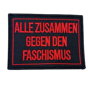 Könnte beinhalten: Schwarzer Stoff-Patch mit rotem gesticktem Text, der "ALLE ZUSAMMEN GEGEN DEN FASCISMUS" lautet.