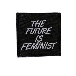 Könnte beinhalten: Schwarzer Stoff-Patch mit weiß gesticktem Text, der "The Future is Feminist" lautet.