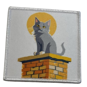 Könnte beinhalten: Eine graue Katze sitzt auf einem Ziegelstein-Schornstein mit einer gelben Sonne dahinter. Die Katze schaut nach rechts und hat einen weißen Fleck auf der Brust.