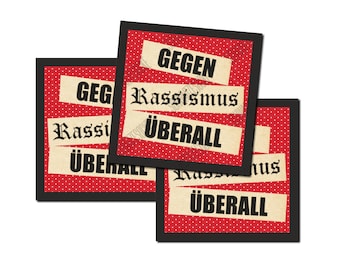 May include: Three square prints with a red polka dot background and black borders. Each print features the words "GEGEN Rassismus ÜBERALL" in a vintage font, advocating against racism.