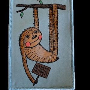 Könnte beinhalten: Gestickter Aufnäher mit einem Cartoon-Faultier, das an einem Ast hängt. Das Faultier ist braun mit rosa Wangen und einem lächelnden Gesicht. Es hält ein Schild mit der Aufschrift "NO NAZIS". Der Aufnäher hat einen hellblauen Hintergrund und einen blauen Rand.