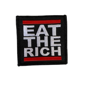 Könnte beinhalten: Schwarzer gestickter Aufnäher mit weißem Text, der "EAT THE RICH" lautet, mit zwei roten Streifen über und unter dem Text.