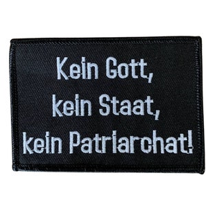 Könnte beinhalten: Schwarzer gestickter Aufnäher mit weißem Text, der "Kein Gott, kein Staat, kein Patriarchat!" lautet.