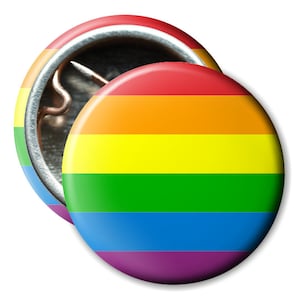 Könnte beinhalten: Zwei runde Ansteckbuttons mit Regenbogenflaggen-Design. Die Buttons haben horizontale Streifen in Rot, Orange, Gelb, Grün, Blau und Lila. Ein Button ist im Fokus, der andere zeigt die Nadel auf der Rückseite.