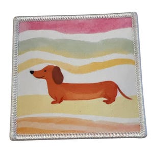 Könnte beinhalten: Ein weißer quadratischer Patch mit weißem Rand, der einen orangefarbenen Cartoon-Dackel zeigt, der auf einem Hintergrund aus bunten Aquarellstreifen in den Farben Rosa, Grün, Gelb und Orange läuft.