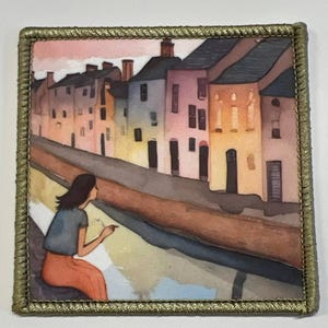 Könnte beinhalten: Ein Aquarellbild einer Frau, die an einem Kanal sitzt und auf eine Reihe bunter Häuser in der Ferne blickt. Der Himmel ist zartrosa und das Wasser ist tiefblau.