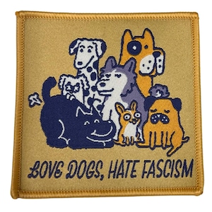 Könnte beinhalten: Quadratischer Aufnäher mit goldenem Rand und Hintergrund. Der Aufnäher zeigt eine Cartoon-Illustration von mehreren Hunden in verschiedenen Farben. Der Text "LOVE DOGS, HATE FASCISM" ist in einer stilisierten Schriftart am unteren Rand des Aufnähers aufgedruckt.