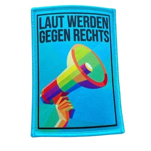 Könnte beinhalten: Ein blauer Patch mit einem Regenbogen-Megaphon und dem Text "LAUT WERDEN GEGEN RECHTS" in Schwarz.