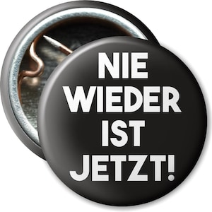 Könnte beinhalten: Schwarzer Knopf mit weißem Text, der "NIE WIEDER IST JETZT!" lautet.
