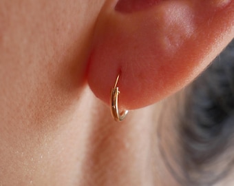 Puede incluir: Primer plano de una oreja con un pequeño aro de oro.