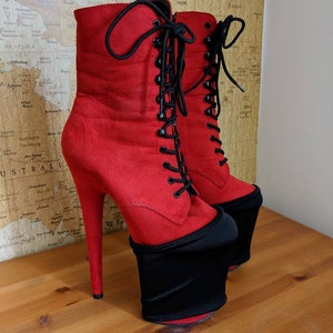 May include: Red suede platform boots with black laces and a thick black platform. The boots have a high heel and a pointed toe.