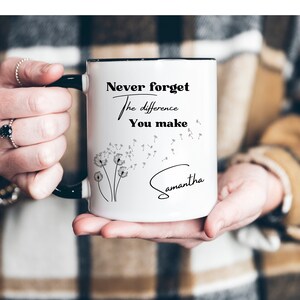 May include: White ceramic mug with a black handle and rim, featuring the text "Never forget the difference You make" and the name "Samantha" in a script font. The design includes a dandelion illustration.