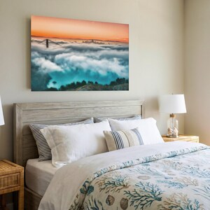 May include: A rectangular wall art print featuring a landscape of the Golden Gate Bridge partially obscured by a thick layer of low-hanging clouds under a vibrant orange sunset sky, with dark green hills visible in the foreground.