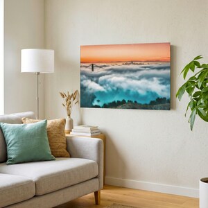 May include: A rectangular wall art print featuring a landscape photograph of the Golden Gate Bridge partially obscured by a thick layer of low-hanging clouds, with a vibrant orange sunset sky above and a deep blue hue in the shadowed areas.