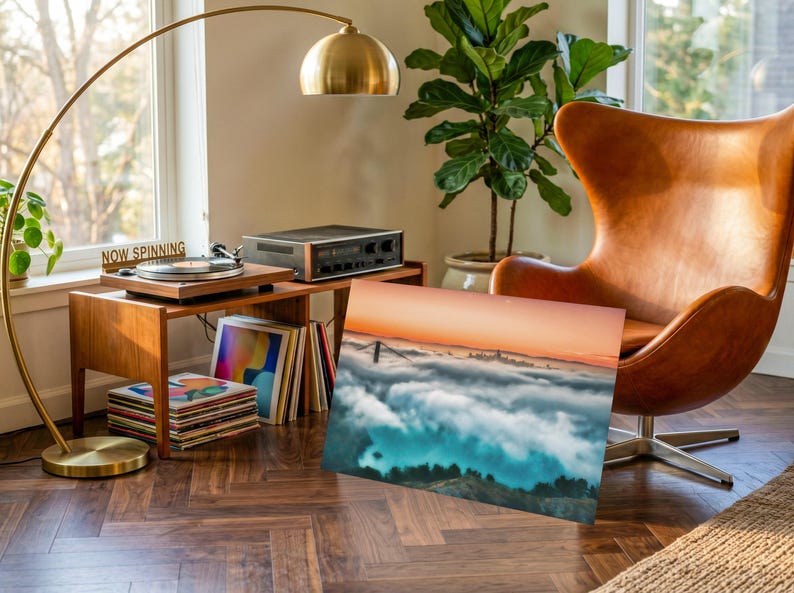 May include: A rectangular wall art print featuring a landscape photograph of a bridge partially obscured by a thick layer of low-hanging clouds at sunrise, with a gradient sky transitioning from orange to blue above the dense white cloud cover.