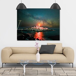 May include: A photograph of a lighthouse on a small island with the Milky Way visible in the night sky. The lighthouse is lit up and reflecting in the water.