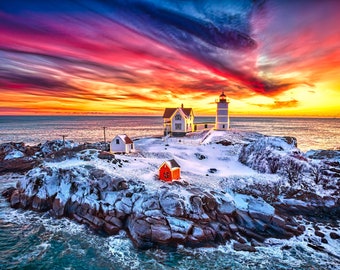May include: A white lighthouse with a red roof stands on a rocky island covered in snow. The sky is a vibrant mix of pink, orange, and blue with dramatic clouds. The ocean is a deep blue and the waves are crashing against the shore.