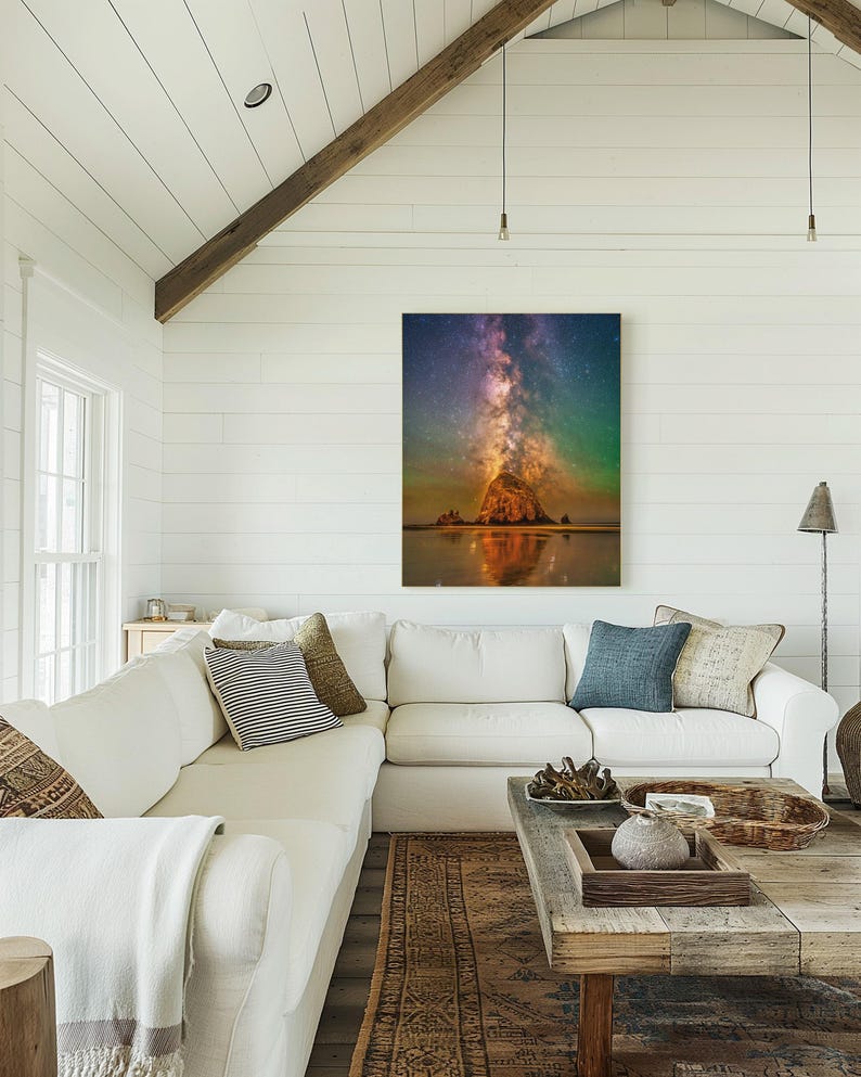 May include: A rectangular wall art print featuring a night sky filled with stars and a vibrant purple and orange nebula above a large rock formation on a beach, with the scene reflected in the wet sand below the rock at the water's edge.