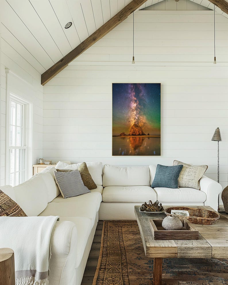 May include: A vertical wall art print featuring a night sky scene with a vibrant purple and orange Milky Way galaxy stretching above a large, illuminated rock formation on a beach, with a clear reflection visible in the wet sand below.