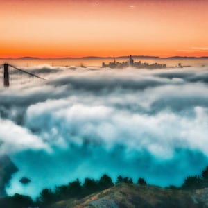 May include: A panoramic view of the Golden Gate Bridge and the San Francisco skyline emerging from a thick layer of low-hanging fog. The scene is illuminated by a vibrant orange sunset sky, contrasting with the deep blue water below the clouds.