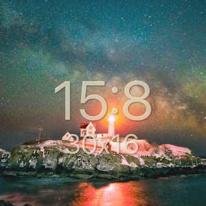 May include: A lighthouse on a rocky island with the Milky Way visible in the night sky. The lighthouse is lit up and the water is reflecting the light. The text "15:8 30x16" is superimposed on the image.