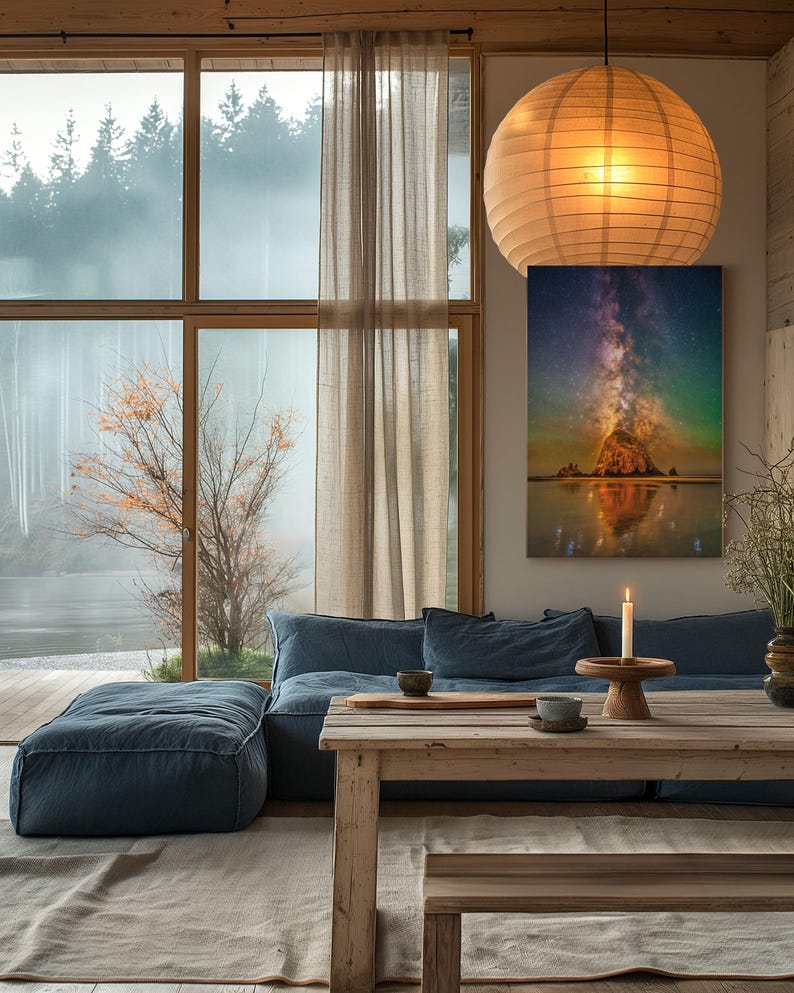 May include: A rectangular wall art print featuring a vibrant night sky with a glowing Milky Way galaxy above a large rock formation on a beach, with reflections on the wet sand, displayed in a room with a blue sofa and wooden furniture.