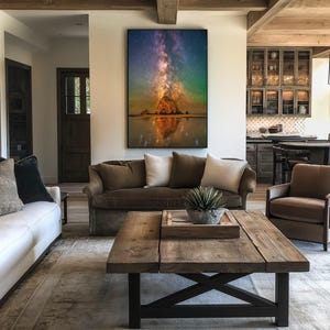 May include: A large rectangular wall art print featuring a vibrant night sky with a purple and orange nebula above a dark rock formation reflected in calm water. The artwork is displayed in a vertical orientation with a thin black frame.