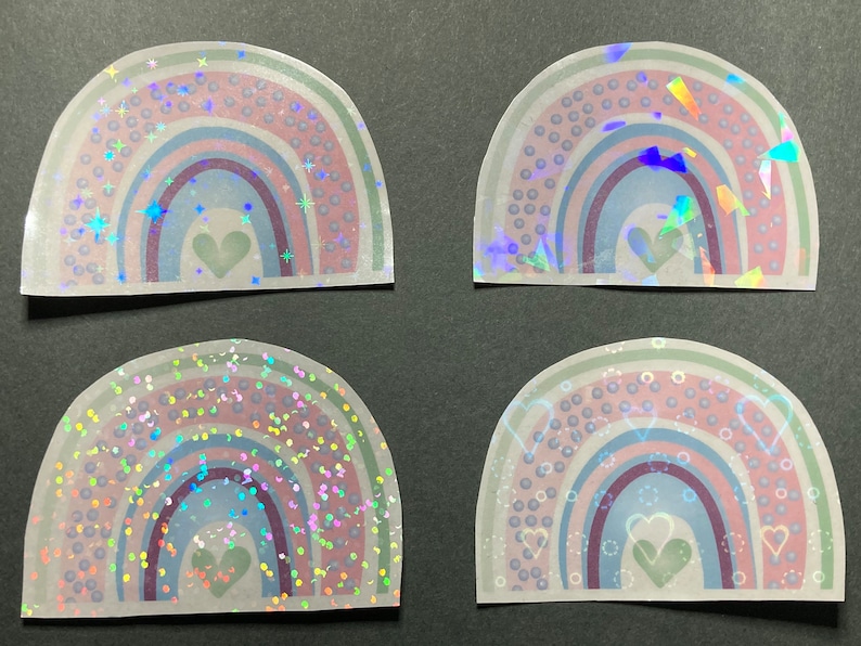 May include: Four iridescent rainbow stickers with a heart in the center. Each sticker has a different holographic pattern, including stars, confetti, and dots.