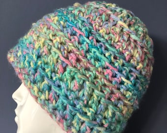 May include: A colorful crocheted beanie hat in shades of blue, green, pink, and yellow. The hat is made with a chunky yarn and has a slouchy fit.