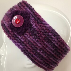 May include: Purple and pink knitted headband with a purple flower and a red heart button.