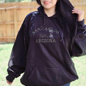May include: A black hoodie with a white graphic print that says "San Carlos Arizona" with a small illustration of cacti and a building.