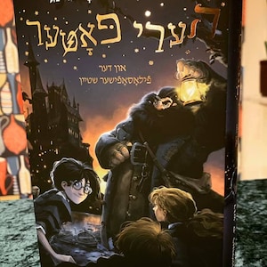 May include: A book cover with a dark background and a gold title that reads "Harry Potter and the Prisoner of Azkaban". The cover features a character with a lantern, a castle in the background, and three children in the foreground.