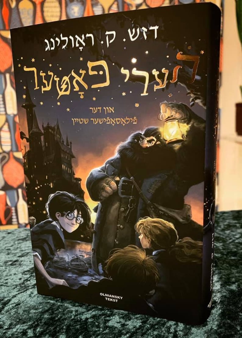 May include: A book cover with a dark background and a gold title that reads "Harry Potter and the Prisoner of Azkaban". The cover features a character with a lantern, a castle in the background, and three children in the foreground.