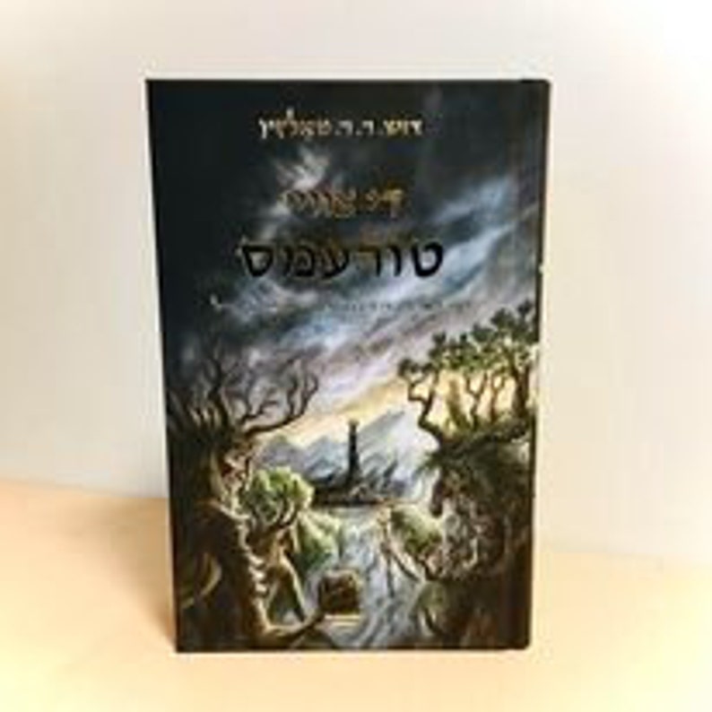 May include: A dark blue book cover with a gold title that reads "The Fellowship of the Ring" and a depiction of a forest scene with a tower in the distance.