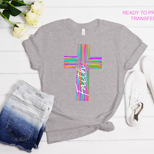 K&ouml;nnte beinhalten: Ein graues T-Shirt mit einem farbenfrohen Kreuzdesign aus vertikalen Streifen in verschiedenen Farben. Das Wort "Faith" ist vertikal in Wei&szlig; auf dem Kreuz geschrieben. Der Text "READY TO PRESS TRANSFER" befindet sich oben rechts.